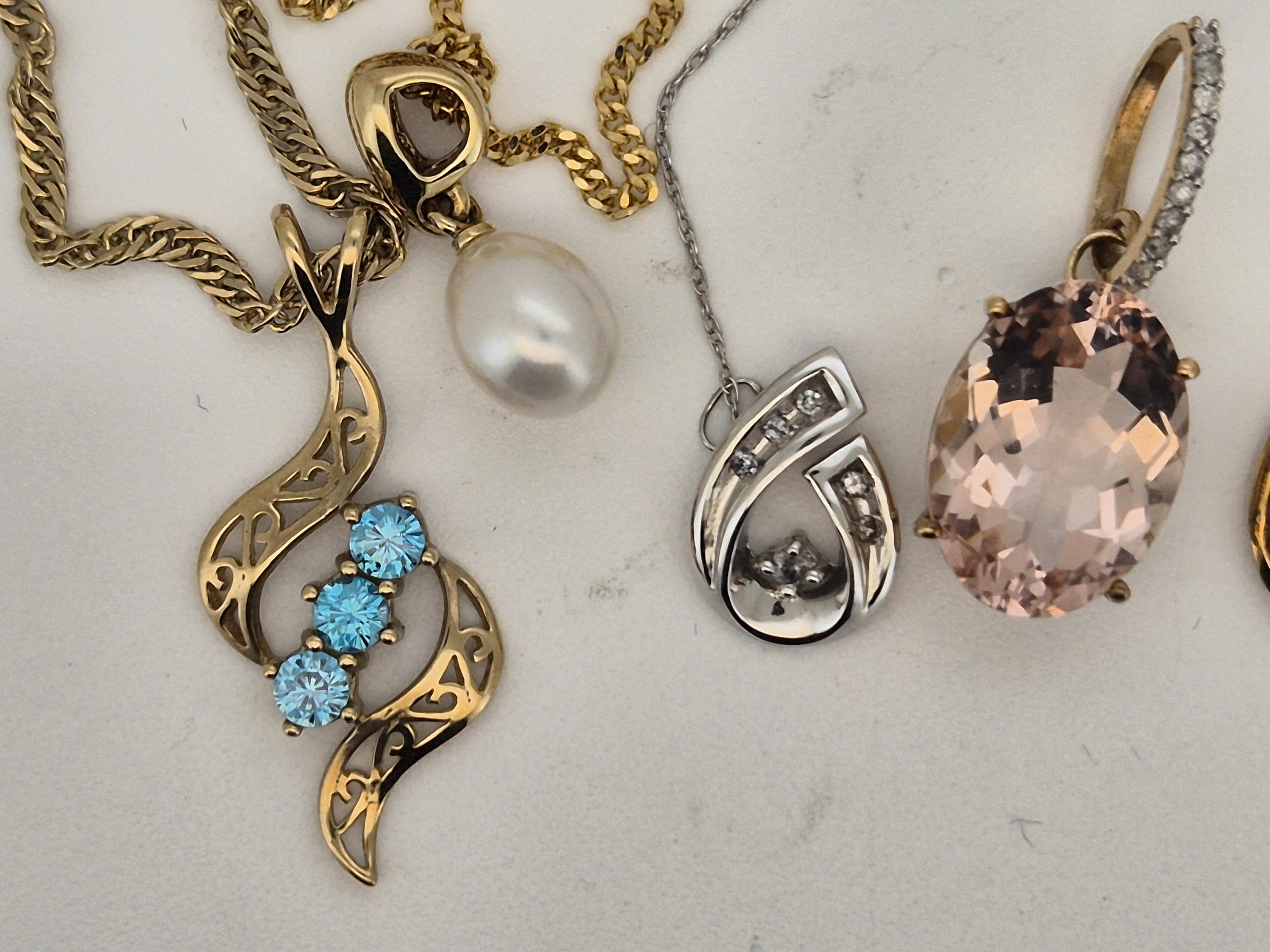 A modern 10k white metal and diamond chip set scroll pendant, 12mm, on a 10k white metal chain, (knotted with a 375 chain), together with three other modern 9ct and gem set pendants, including cultured pearl, all with 9c